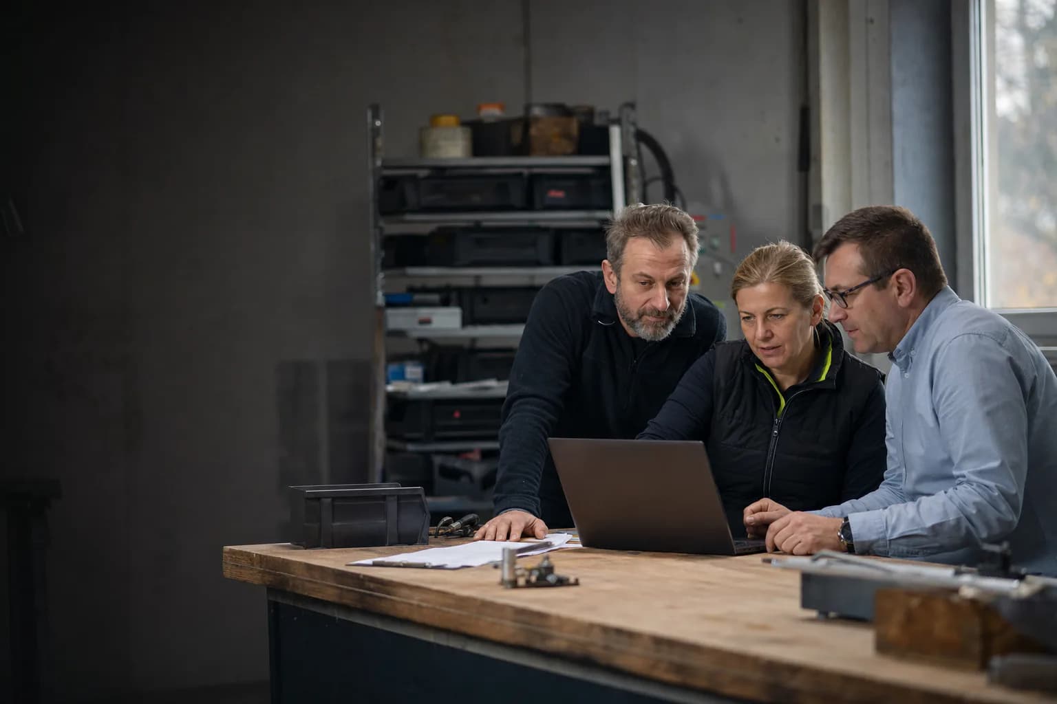 Zespół firmy technicznej i klient wspólnie sprawdzają status zlecenia na laptopie